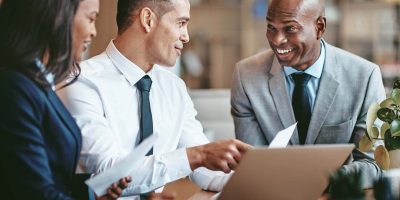 A group of people in business attire looking at a laptop screen